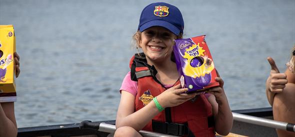 Kid holding easter egg up in a canoe