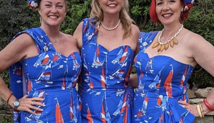 3 women pose for the cameria in their union jack coloured outfits