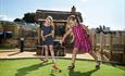 Two young girls having fun whilst putting their balls on the crazy golf course