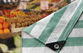 Folded market tarpaulin with fresh fruit and veg in background.