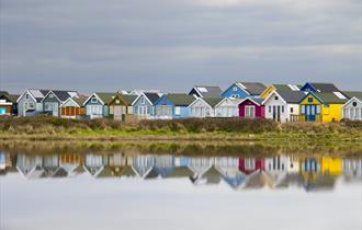 Colourful Mudeford beach huts in a row.