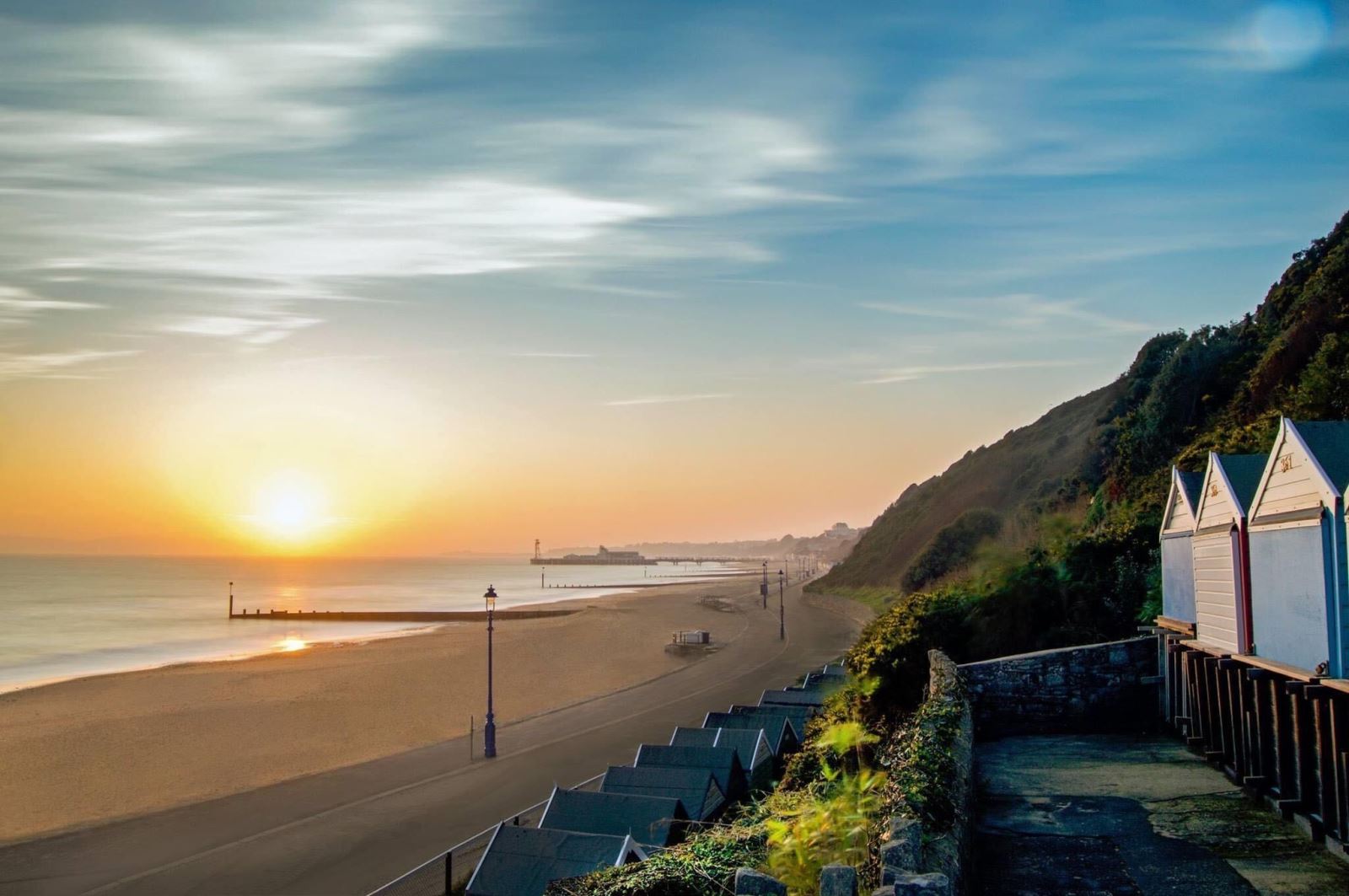 The sun hangs low over the promenade of Bournemouth Beach