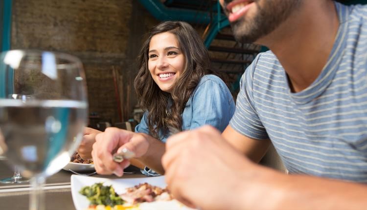 Couple enjoying a sit down meal and a glass of wine each