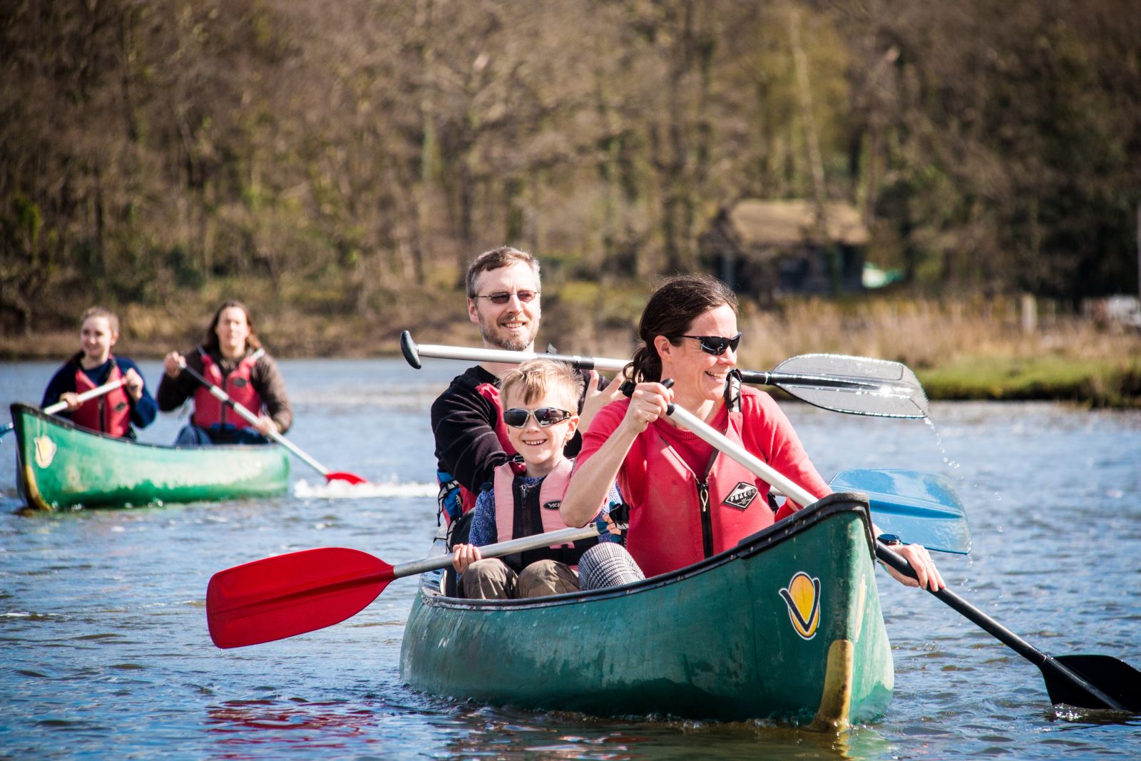 a family canoeing on a lake looking happy