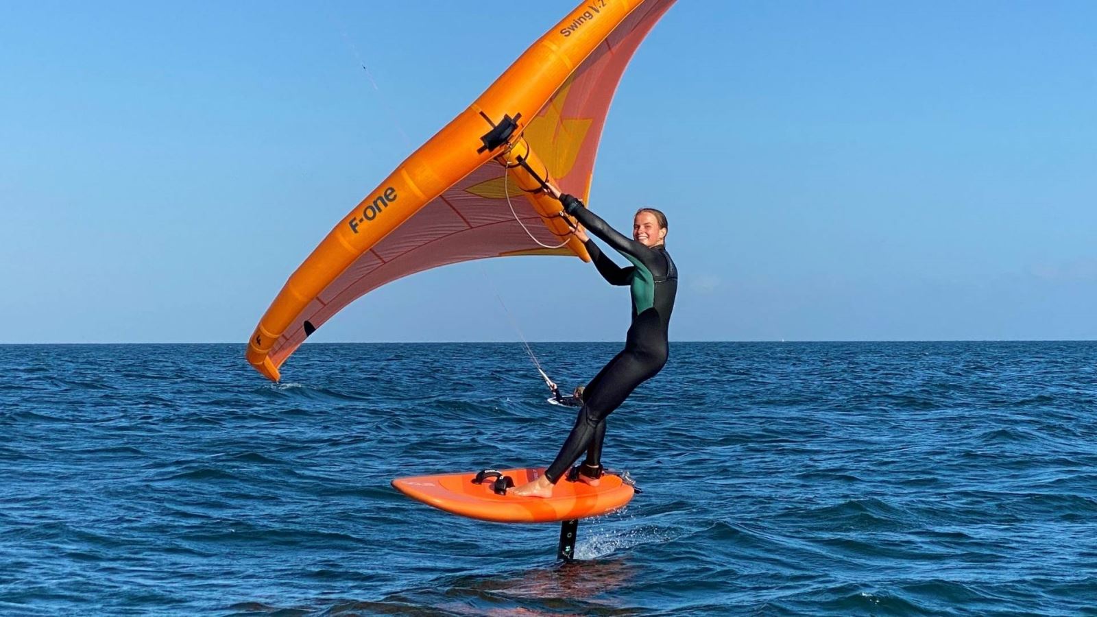 Woman enjoying her time wing foiling on the sea 