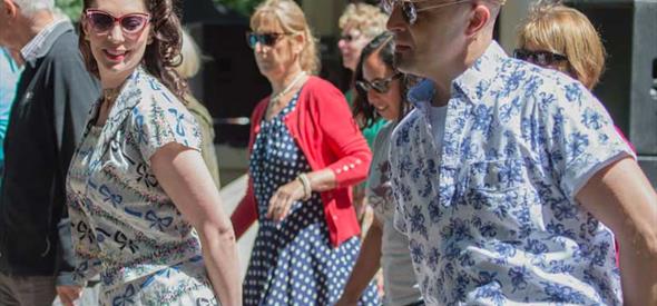 A close-up group of people with hands behind their backs dancing