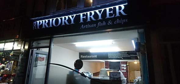Priory fish and chips lit up at night.