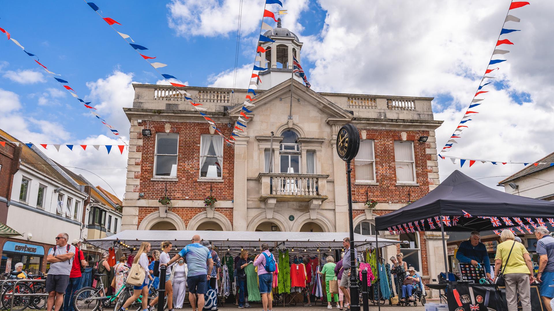 Market stalls and visitors line the streets in Christchurch with Saxon square in the background