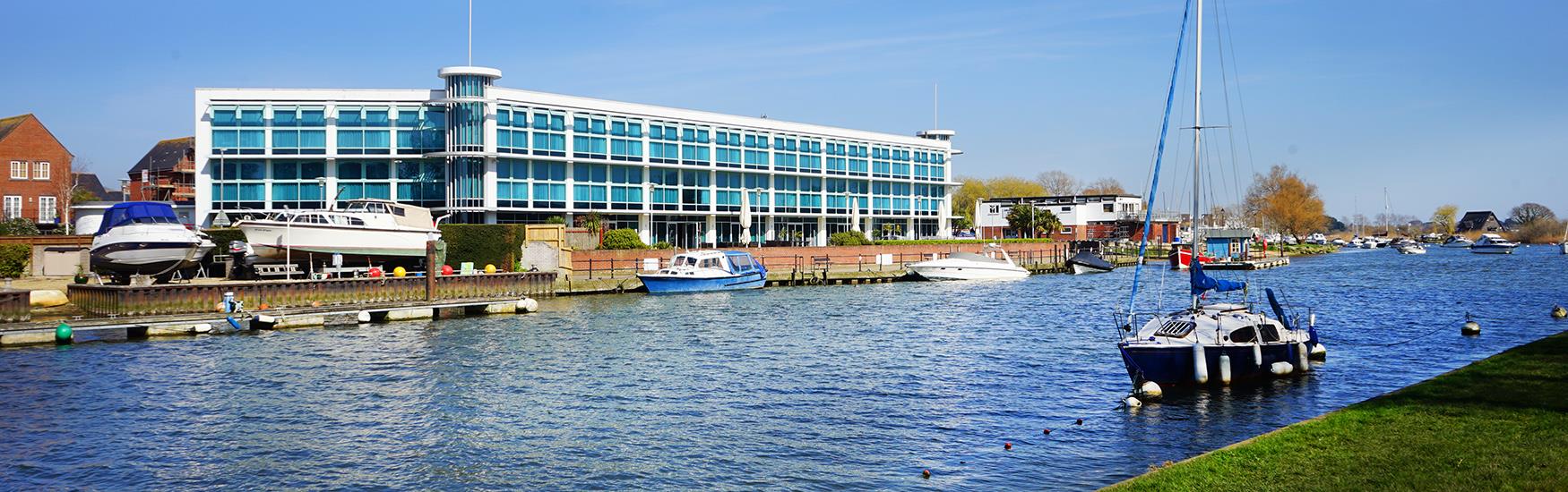 Captains Club Hotel in Christchurch shot from across the water with Boats moored next to it