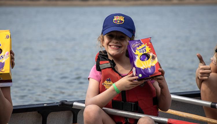 Kid holding easter egg up in a canoe