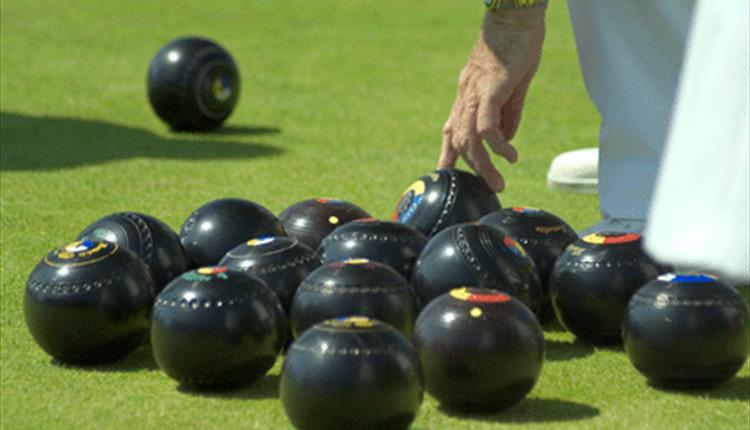 man reaching down to a bowls ball.