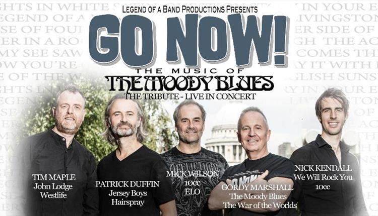 Five men standing in black t-shirts with a concert venue in the background
