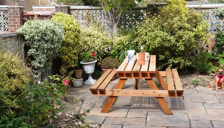 Cosy garden with wooden seating area surrounded with plants and trees