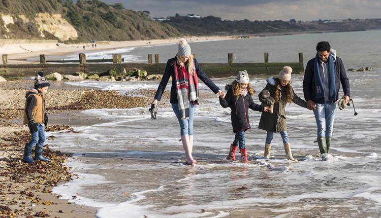 Family wrapped up warm whilst dipping their feet in the sea