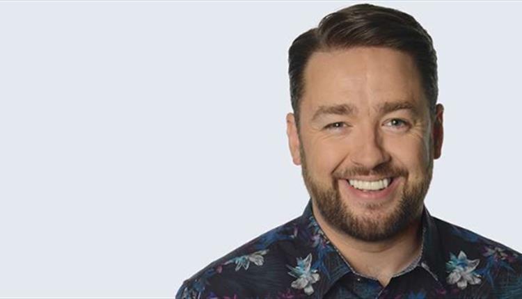 A man with a flowery shirt on, smiling at the camera.