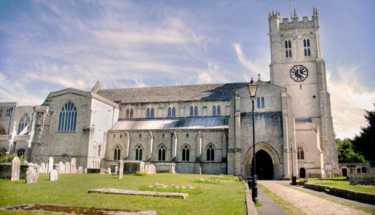 The North side and entrance to Christchurch Priory on a brightly lit day.