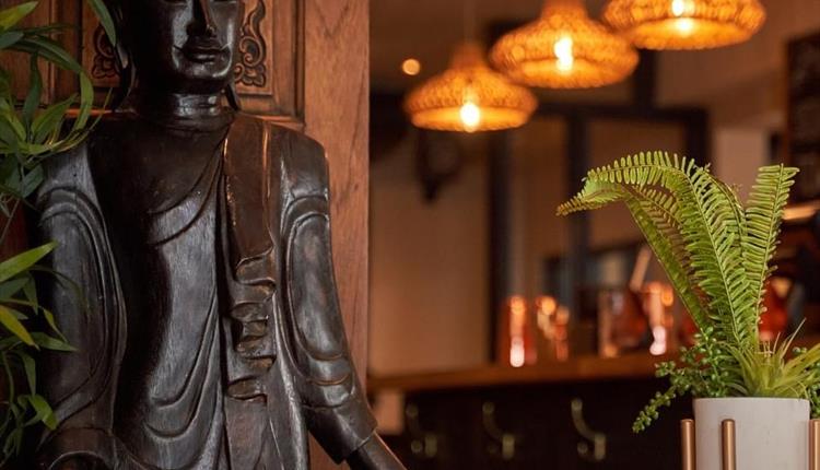 Nusara Thai restaurant with a thai statue and warm lighting and plants