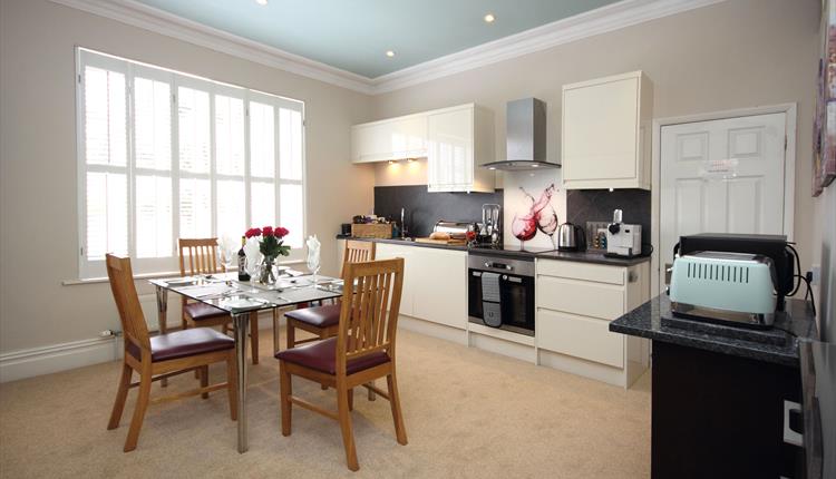 Kitchen with appliances and glass table and wooden chairs