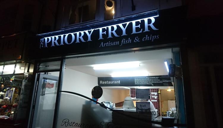 Priory fish and chips lit up at night.