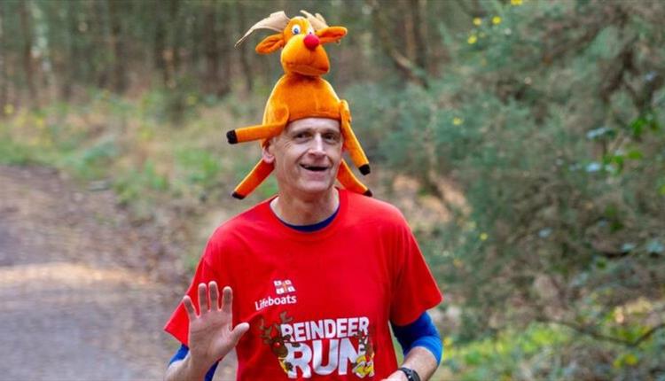 man running with a christmas hat on in the forest