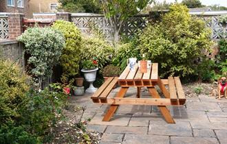 Cosy garden with wooden seating area surrounded with plants and trees