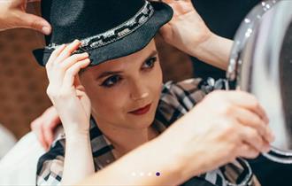 Girl holding a hat looking into the mirror