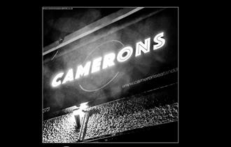 Camerons lit up sign in black and white.