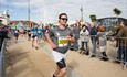 Man looking happy with sunglasses running with the big wheel behind him