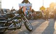 Old black bike parked up with riders admiring in the background