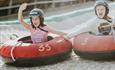Two girls going down the dry ski slope together on their ringos