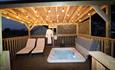 Cosy hot tub with two chairs under warm lighting