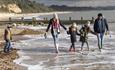 Family wrapped up warm whilst dipping their feet in the sea