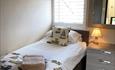 Single bed with fresh colours and bedside drawers and cosy lamp