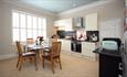 Kitchen with appliances and glass table and wooden chairs