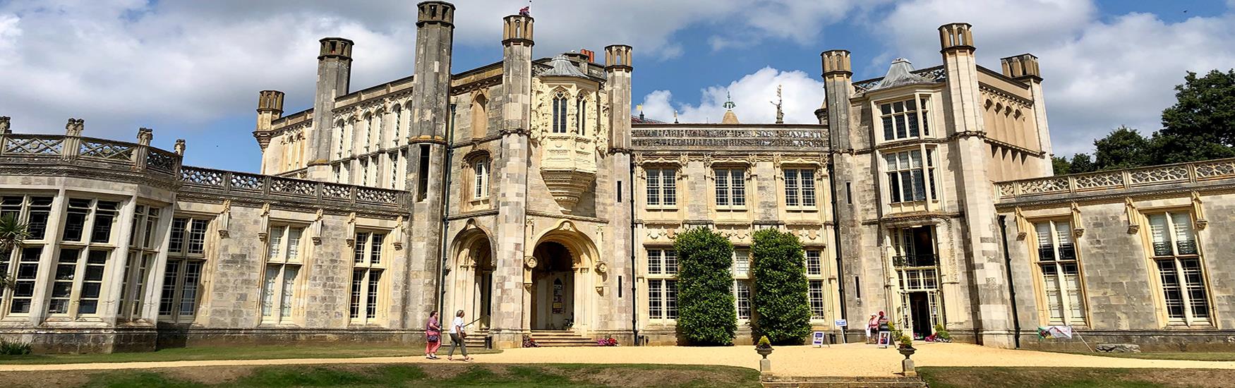 Lovely sunny shot of Highcliffe castle with vistors sitting in the sun outside