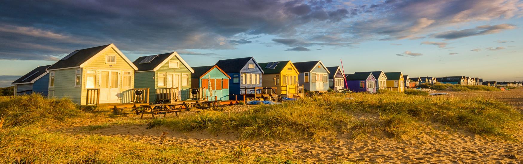Sunset over the colourful array of beach huts located along a Christchurch beach