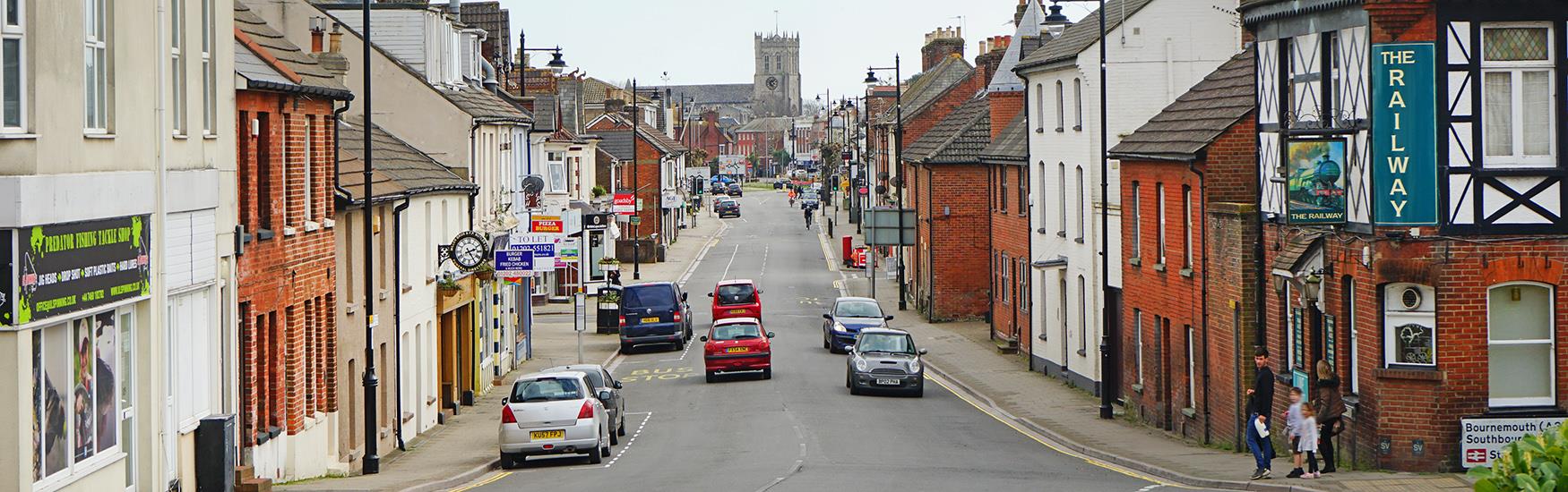 Main road into Christchurch high street with pubs and the priory in the background