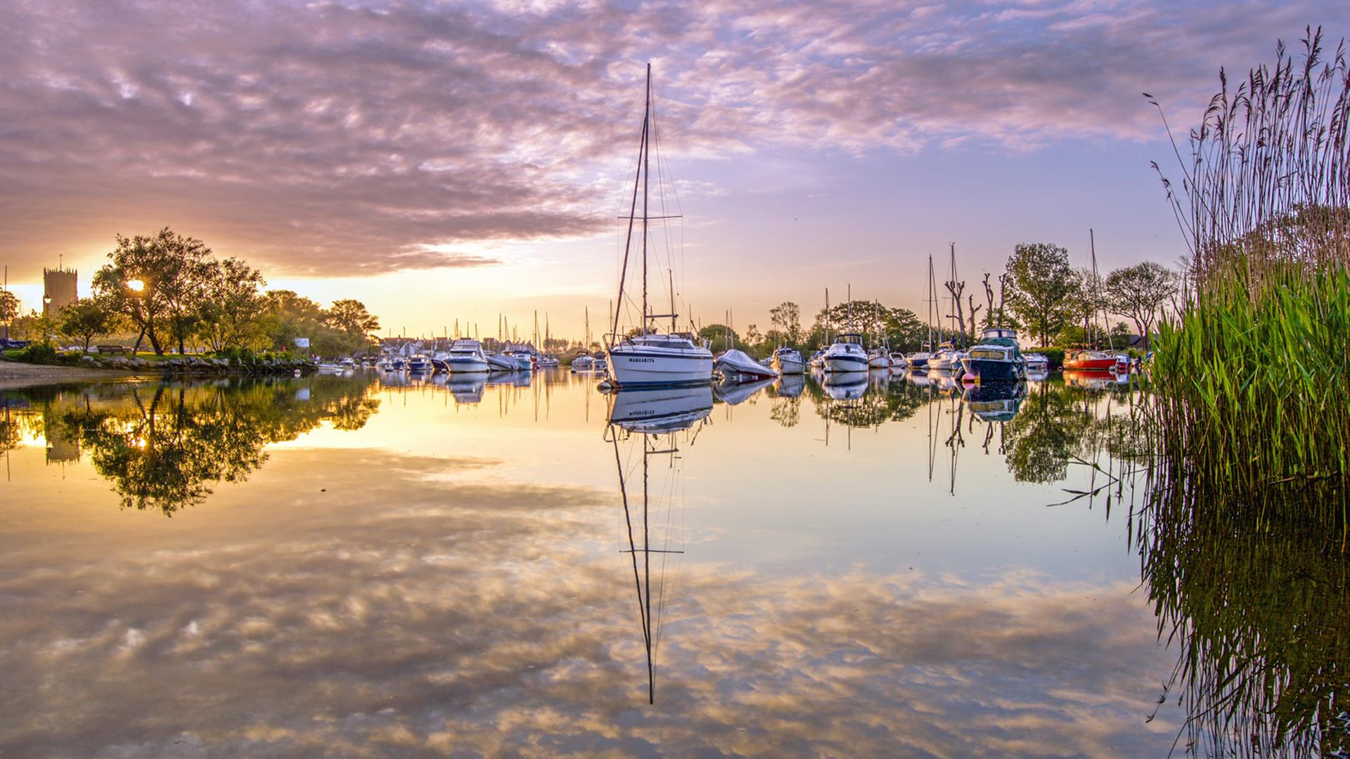 Boats moored in Christchurch harbour with sunsetting behind