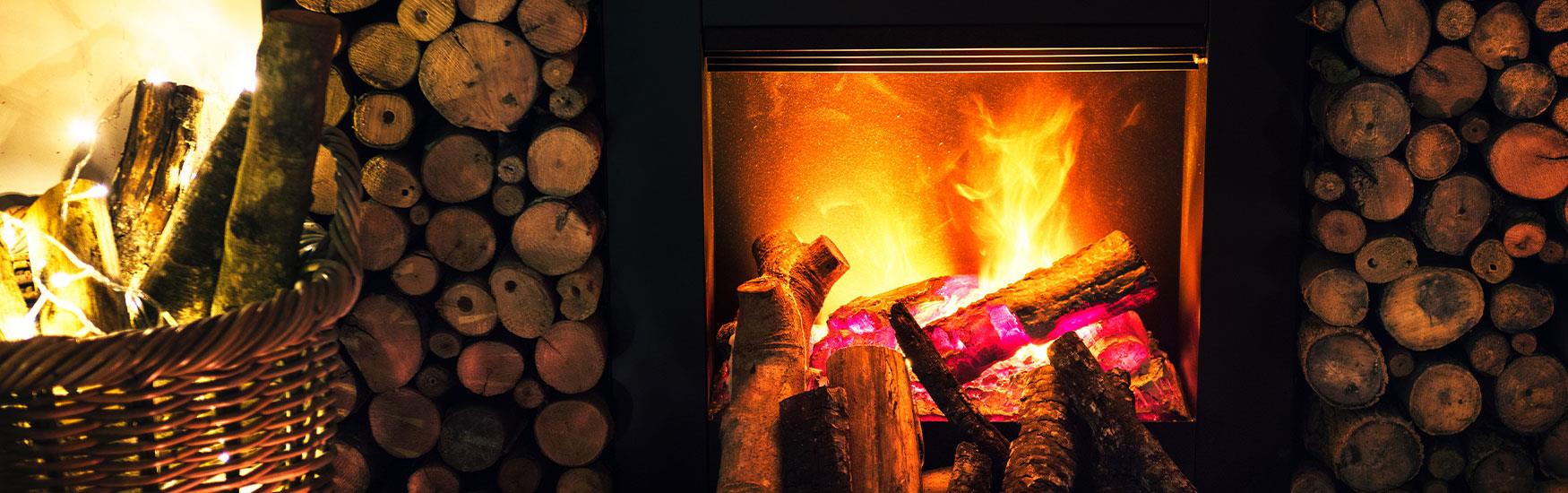 Generic winter shot of a warm yet festive fireplace glowing orange with logs surrounding it