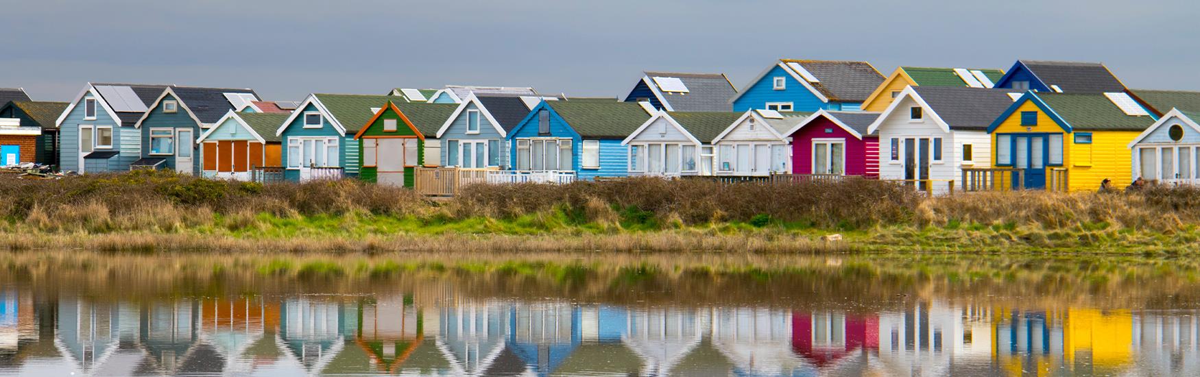 Winter shot of the multi-colour Mudeford beach huts in Christchurch reflecting off the sea