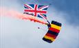 Parachutist dropping into Bournemouth with a union jack and smoke attached to him
