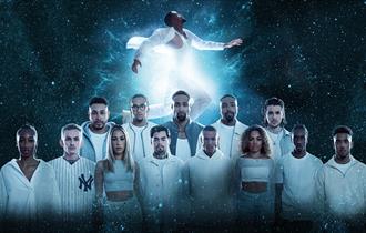 The diversity dance team all wearing white with a space-like background