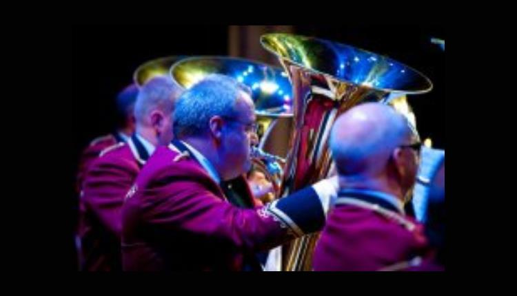Group of men playing large brass instrument in spotlight