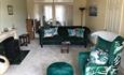 Large lounge with sofa, green chair and footstool with flower details