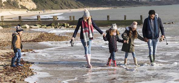 Family wrapped up warm whilst dipping their feet in the sea
