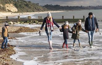 Family wrapped up warm whilst dipping their feet in the sea