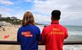 A lifeguard and a Kidzone ranger look out on Bournemouth beach in their red and blue t shirts