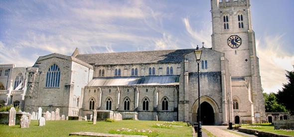 The North side and entrance to Christchurch Priory on a brightly lit day.