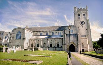 The North side and entrance to Christchurch Priory on a brightly lit day.
