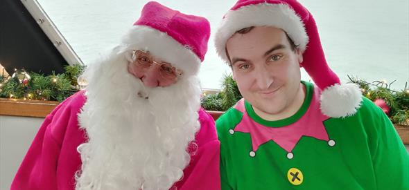 Santa and a elf smiling at the camera 